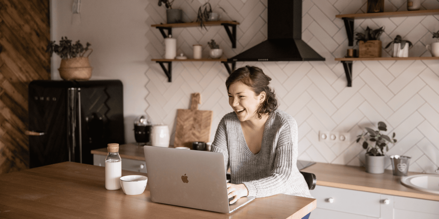 Woman using a laptop in a kitchen setting