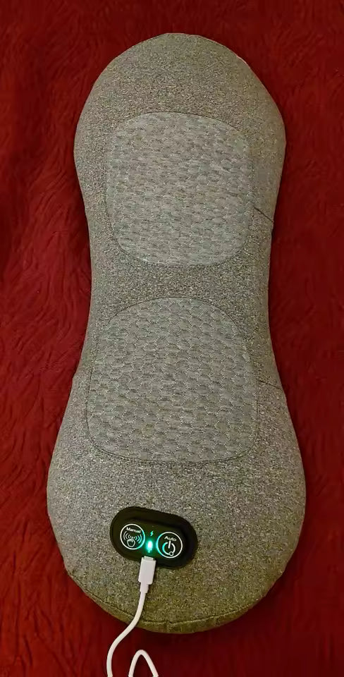 Gray electric massager pad with power cord on a red surface