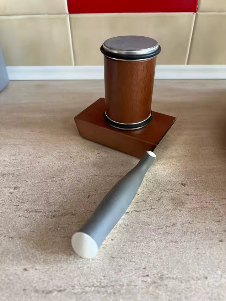 Brown cylindrical object with a gray handle on a beige carpet