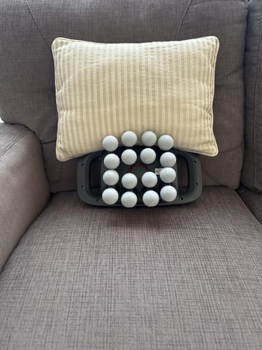 Massage pillow with white balls on a gray couch